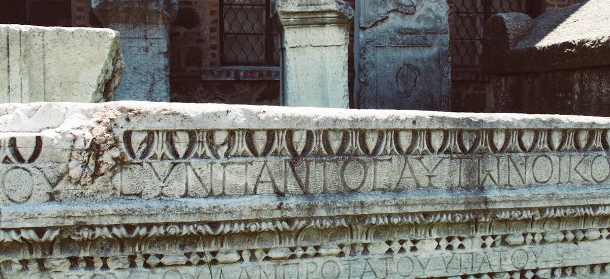 Close-up of an ancient Roman stone inscription with intricate carvings and Latin text.