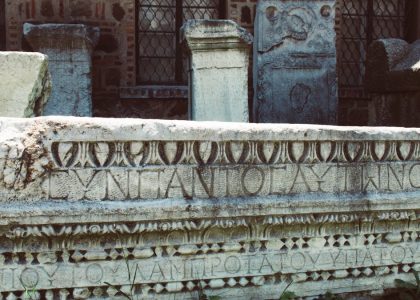 Close-up of an ancient Roman stone inscription with intricate carvings and Latin text.
